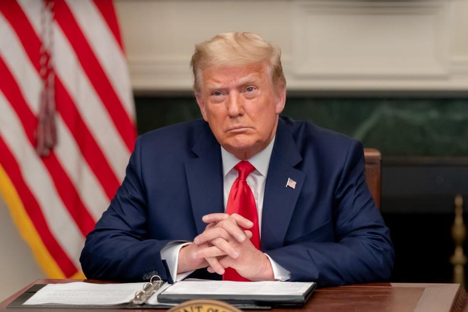 Former President Donald Trump teleconferencing with American troops while seated at his desk.