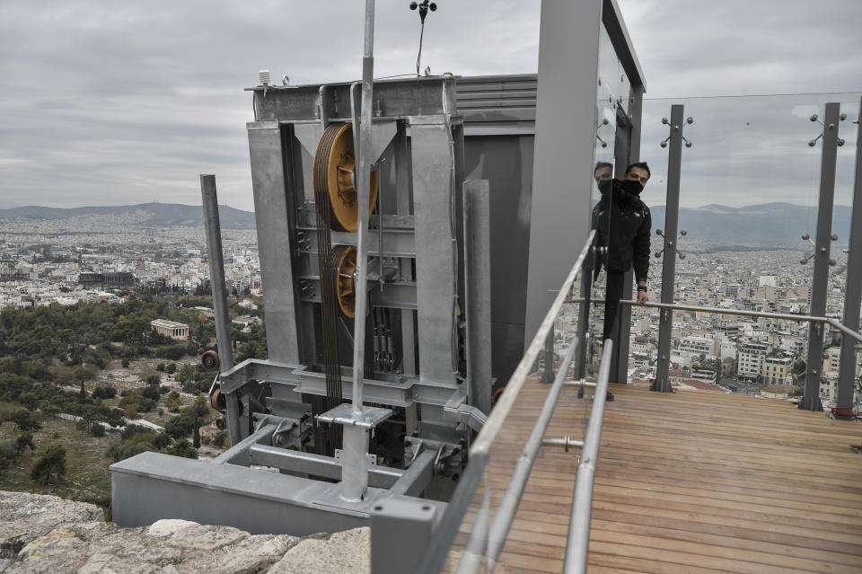 A man stands inside the new elevator at the Acropolis Archaeological site in Athens, Thursday, Dec 3, 2020. Acropolis became fully accessible for people with disabilities after a restoration of the pathways and the inauguration of a new elevator. (Louisa Gouliamaki/Pool via AP)