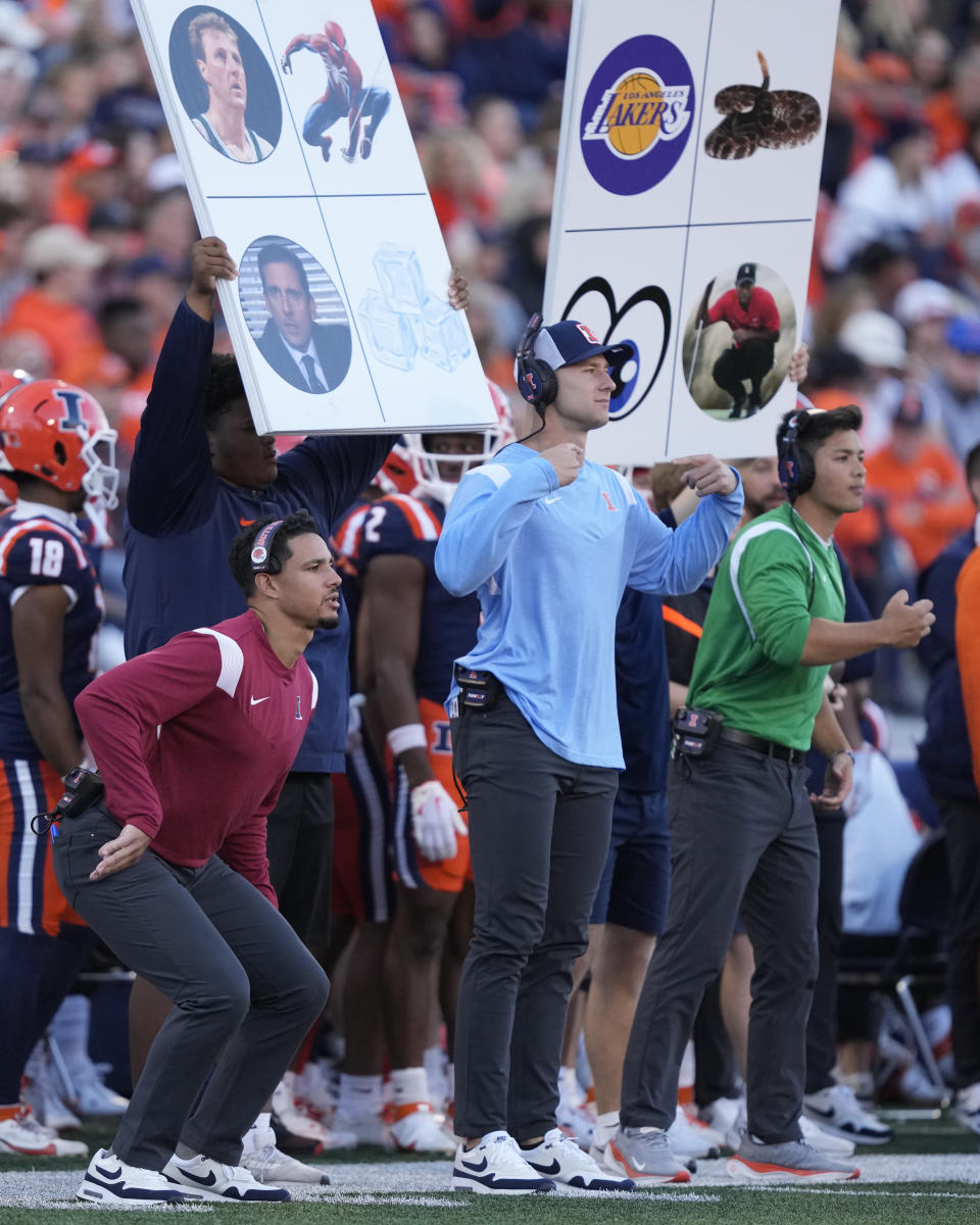 FILE - Members of the Illinois football team send in signals during an NCAA college football game against Wisconsin Saturday, Oct. 21, 2023, in Champaign, Ill. NCAA investigators interviewed members of Michigan football coach Jim Harbaugh’s staff about a sign-stealing scheme on Wednesday, Oct. 25, 2023, a person familiar with the governing body’s visit told The Associated Press. The NCAA does not directly ban the stealing of signs, but there are rules against using electronic equipment to record an opponent’s signals and in-person, advanced scouting of future opponents in season. (AP Photo/Charles Rex Arbogast, File)