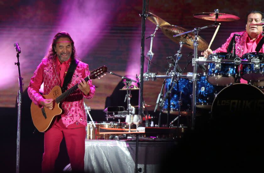 Los Bukis frontman and co-founder Marco Antonio Solis, left, and drummer Pedro Sanchez, right, play with the legendary Mexican grupera band for their Una Historia Cantada Tour at the Los Angeles Coliseum on Thursday, Aug. 18, 2022.