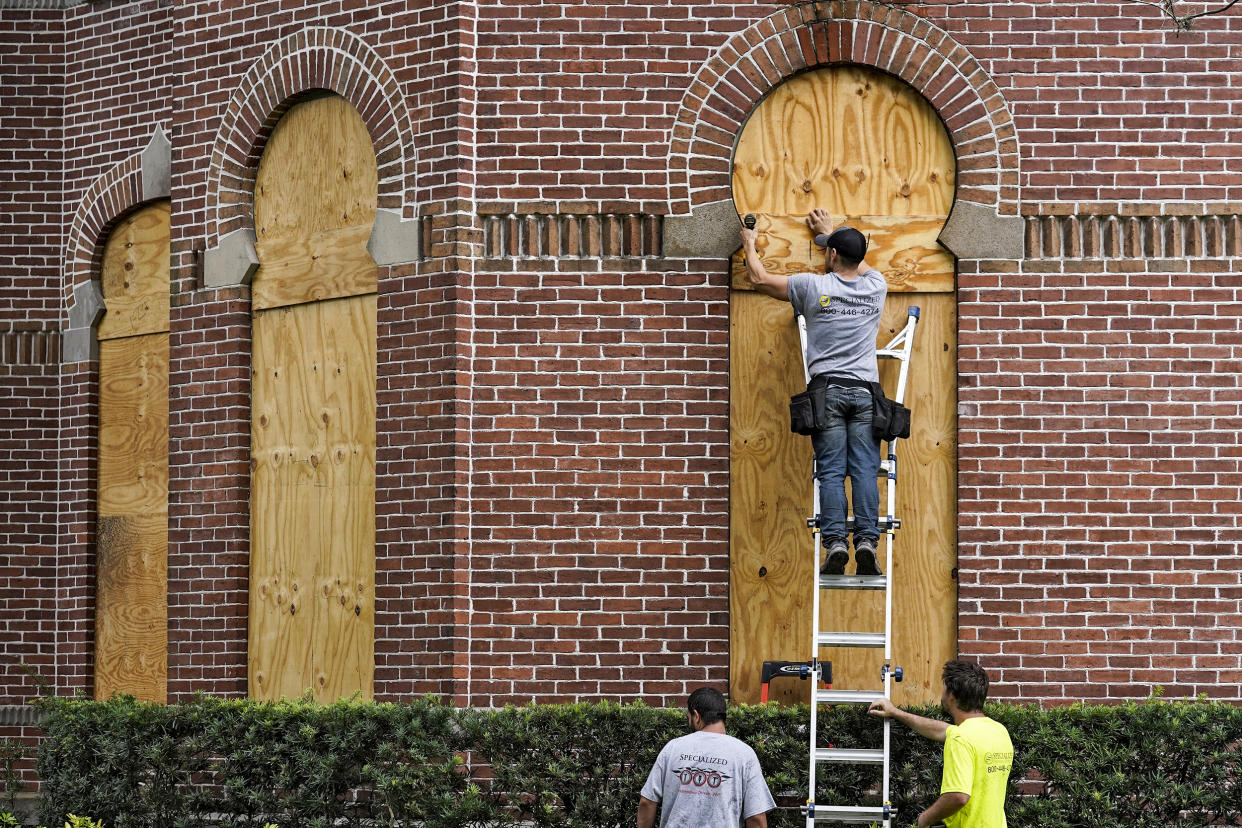 Workers from Specialized Performance Delivered 24:7 board up the windows on the historical Henry B. Plant Hall on the campus of the University of Tampa ahead of Hurricane Ian on Sept. 27, 2022, in Tampa, Fla. (Chris O'Meara / AP)