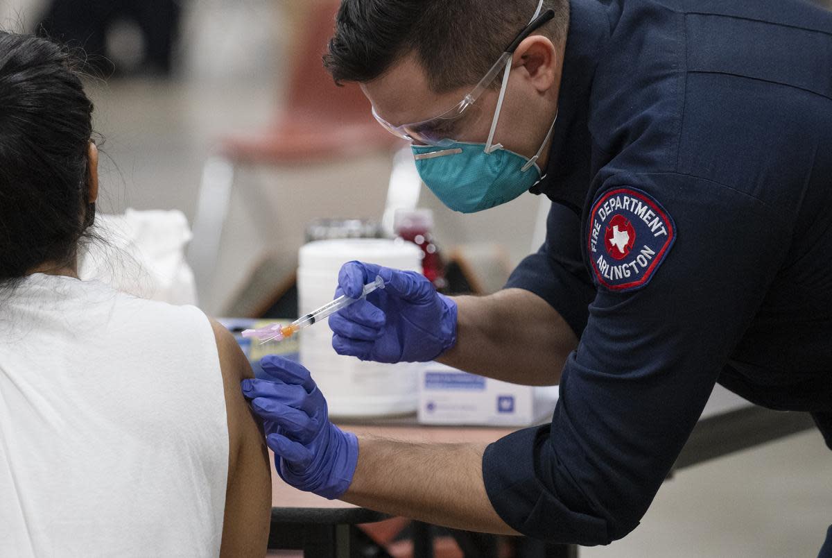 Arlington Fire Fighter Samuel Rochin, right, administers a COVID-19 vaccine to healthcare worker Vannia Atao at the Esports Stadium in Arlington on Jan. 05, 2021.