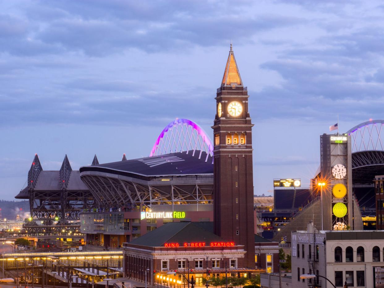 he historic King Street Station is seen during the nighttime with CenturyLink Field and Safeco Field in the distance.