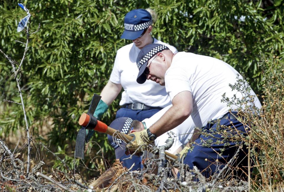 Police search bushes for traces of the missing girl in Portugal in June 2014. (Rex)