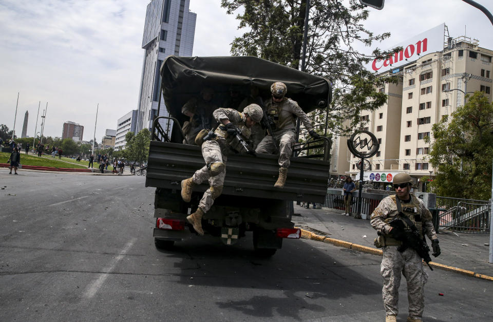 Chilean Army soldiers jump from a truck during a protest in Santiago, Chile, Saturday, Oct. 19, 2019. The protests started on Friday afternoon when high school students flooded subway stations, jumping turnstiles, dodging fares and vandalizing stations as part of protests against a fare hike, but by nightfall had extended throughout Santiago with students setting up barricades and fires at the entrances to subway stations, forcing President Sebastian Pinera to announce a state of emergency and deploy the armed forces into the streets. (AP Photo/Esteban Felix)
