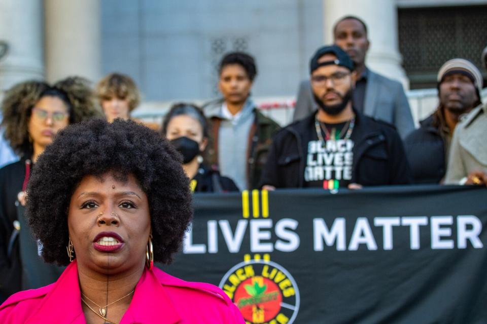 A woman in a pink jacket speaks outside L.A. City Hall.