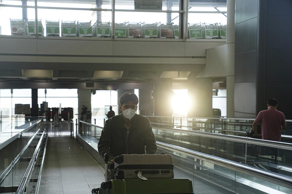 A passengers walks along a bridge in Hong Kong international airport in Hong Kong, Friday, Sep. 23, 2022. Hong Kong’s leader announced the city would no longer require incoming travelers to quarantine in designated hotels as the city seeks to open up globally after nearly two years. The measures will come into effect Monday.(AP Photo/Lam Yik)