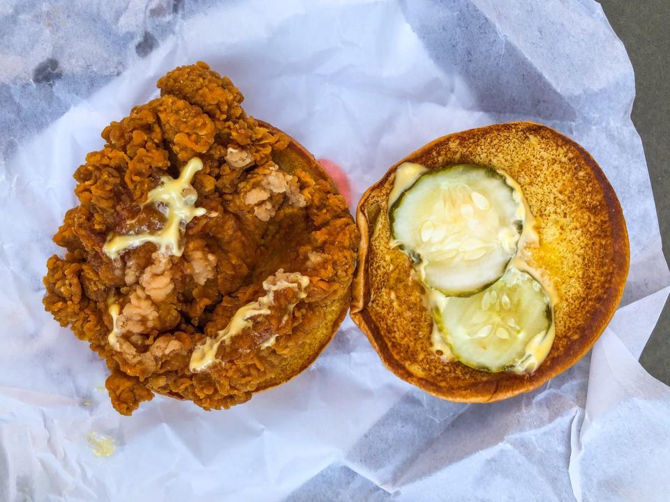 On the left, a large fried-chicken fillet and some yellow sauce on a bun of Burger King's Ch'King sandwich. On the left, a bun half with two medium pickle slices and yellow sauce.