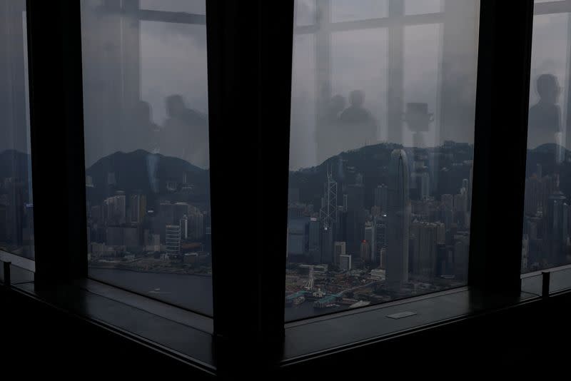 The reflection of tourists gazing at the scenic view of the city is captured on the glass windows of the observation deck in Hong Kong