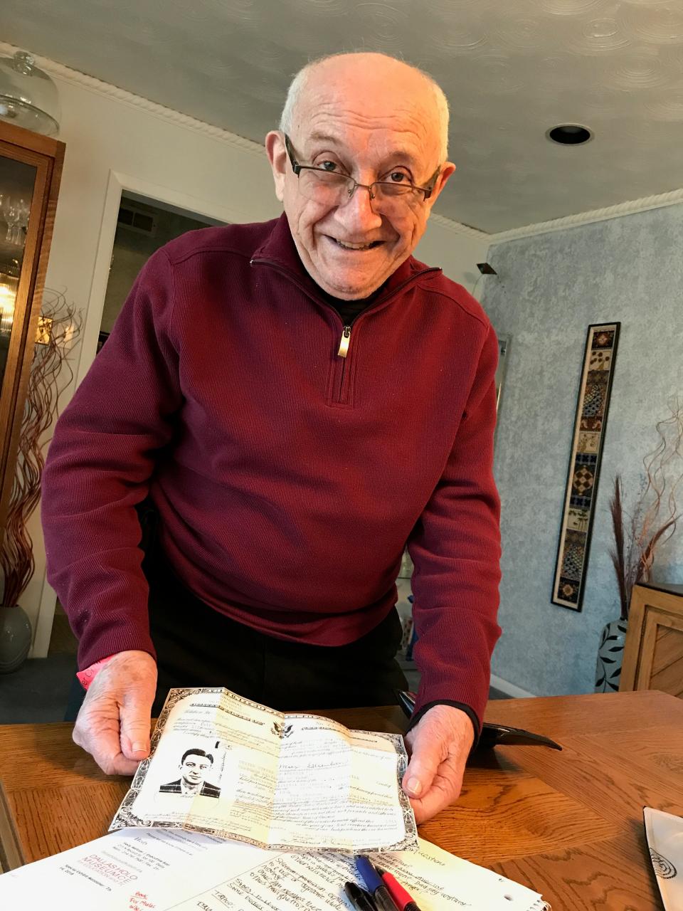 Max Glauben displays his naturalization papers at his dining room table in 2018.