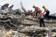 Members of police K-9 squad lead a sniffer dog during a search for victims at a hospital building collapsed in Friday's earthquake in Mamuju, West Sulawesi, Indonesia, Sunday, Jan. 17, 2021. Rescuers retrieved more bodies from the rubble of homes and buildings toppled by the 6.2 magnitude earthquake while military engineers managed to reopen ruptured roads to clear access for relief goods. (AP Photo/Yusuf Wahil)