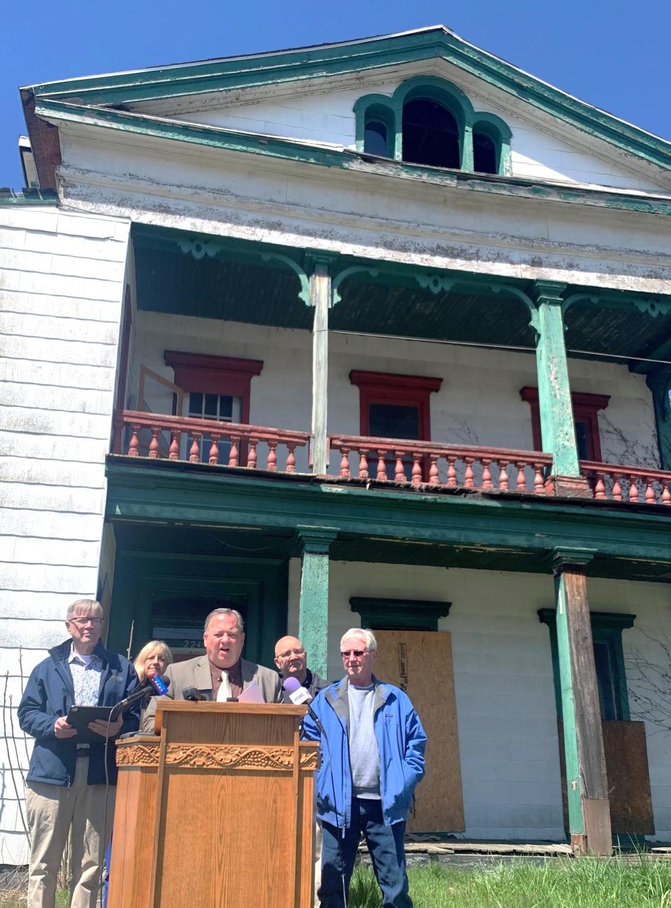 Elmira Mayor Dan Mandell, joined by other city officials, discusses a new initiative to improve the city's housing stock, while standing in front of a long-vacant house at the corner of First Street and College Avenue.