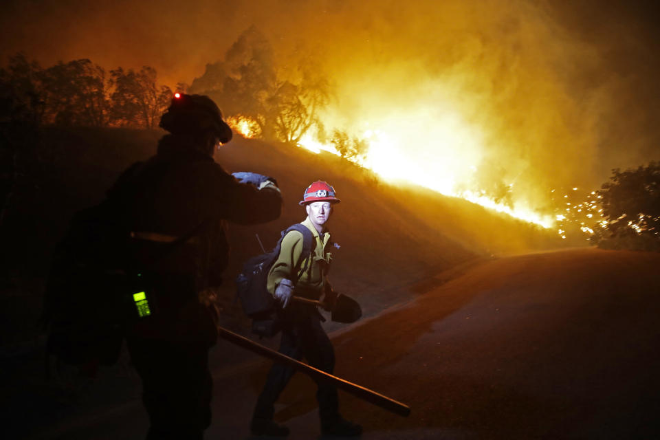 Firefighters walks on a road leading to a residence as the Maria Fire burns on a hillside Thursday, Oct. 31 2019, in Somis, Calif. (AP Photo/Marcio Jose Sanchez)