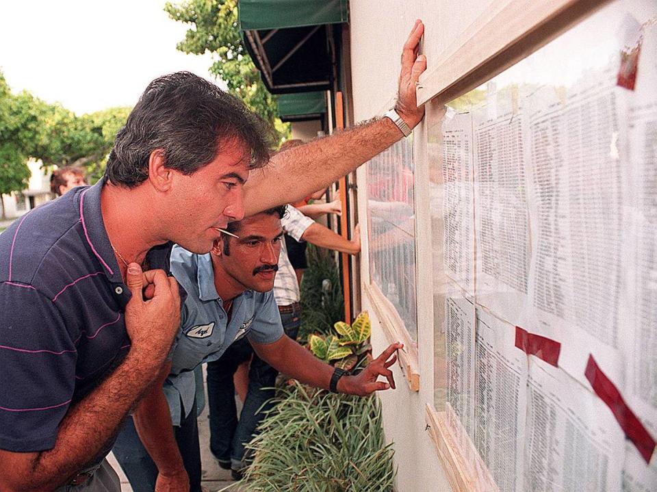 Angel Cambara y Alfredo Bernal revisan una lista de balseros cubanos detenidos en la Base Naval de Guantánamo, en las paredes de Radio Mambí (WAQI), en una foto de archivo.