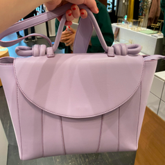 me holding the lilac bag with top flap and top handle with knotted details