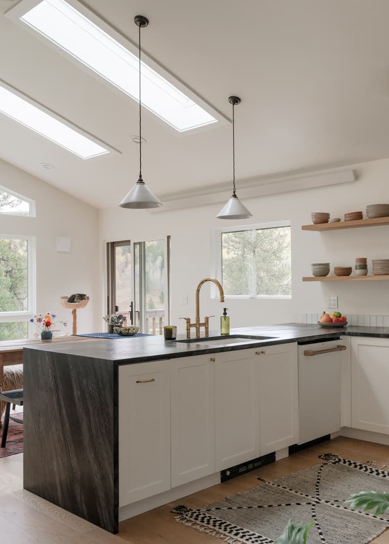 Pendant lamps hanging over sink island area in light filled kitchen.