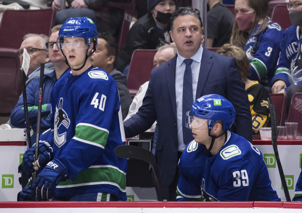 FILE - Vancouver Canucks coach Travis Green, upper right, stands on the bench behind Elias Pettersson (40) and Alex Chiasson (39) during the third period of an NHL hockey game against the Pittsburgh Penguins, Dec. 4, 2021, in Vancouver, British Columbia. The New Jersey Devils have fired coach Lindy Ruff. Current Devils assistant Green has been named as the interim replacement. General manager Tom Fitzgerald made the stunning move with less than 30 games left in the NHL season. (Darryl Dyck/The Canadian Press via AP, File)