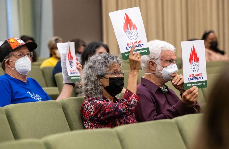 Climate advocates holds signs during the Sacramento City Council meeting Tuesday where residents were able to attend in-person for the first time since the beginning of the pandemic. Mask are required and the chambers was kept at half capacity.