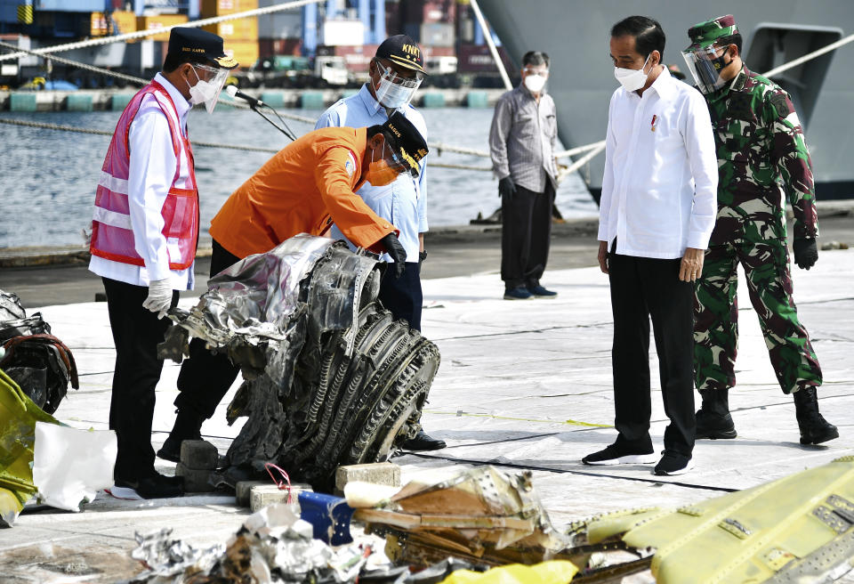 In this photo released by the Indonesian Presidential Palace, President Joko Widodo, second right, listens to an explanation from the Chief of National Search and Rescue Agency Bagus Puruhito, second left, as Transportation Minister Budi Karya Sumadi, left, Chairman of the National Transportation Safety Committee Soerjanto Tjahjono, third left, and Navy Chief of Staff Adm. Yudo Margono, right, look on, as they inspect pieces of the Sriwijaya Air flight SJ-182 retrieved from the Java Sea where the passenger jet crashed on Jan. 9, at Tanjung Priok Port in Jakarta, Indonesia, Wednesday, Jan. 20, 2021. The Indonesian leader on Wednesday reassured relatives of the passengers killed when the plane nosedived into the Java Sea that compensation is paid to family members struggled with grief. (Laily Rachev, Indonesian President Palace via AP)