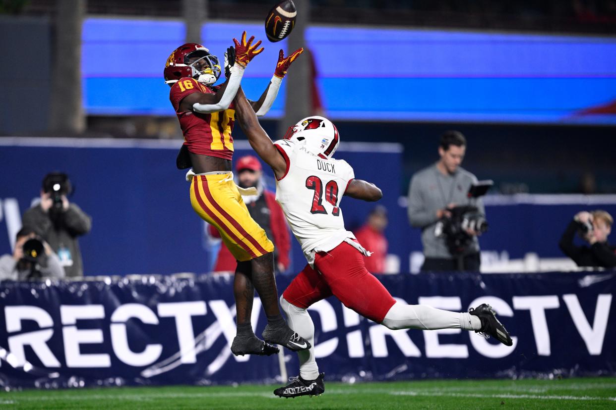 Dec 27, 2023; San Diego, CA, USA; USC Trojans wide receiver Tahj Washington (16) catches a touchdown over Louisville Cardinals defensive back Storm Duck (29) during the first half at Petco Park. Mandatory Credit: Orlando Ramirez-USA TODAY Sports