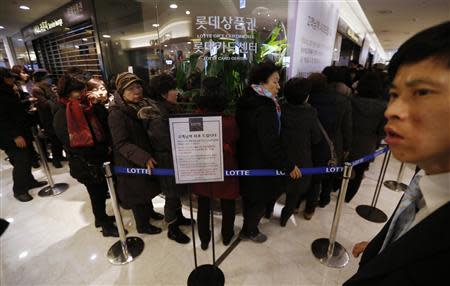 An apology (C) to customers is displayed as customers wait in a line to apply for their credit cards to be reissued at Lotte Card's main office in Seoul January 21, 2014. REUTERS/Kim Hong-Ji