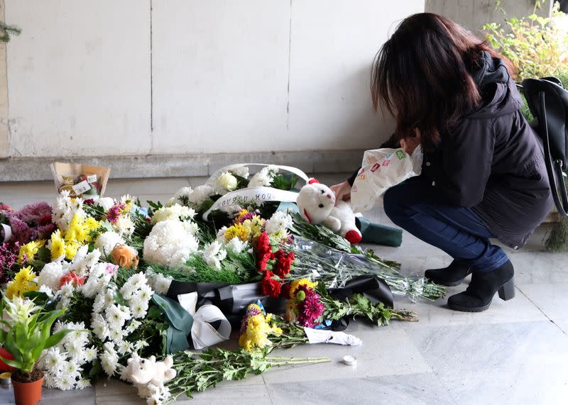 Woman places a teddy bear at a makeshift memorial for the victims of a bus accident, in Sofia