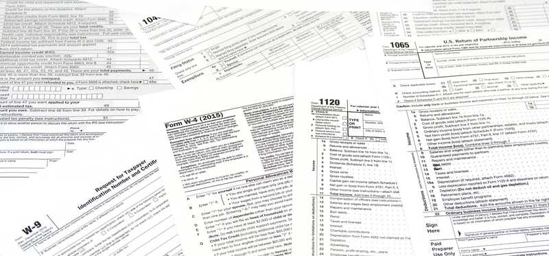 An assortment of paper tax forms lay in a pile.