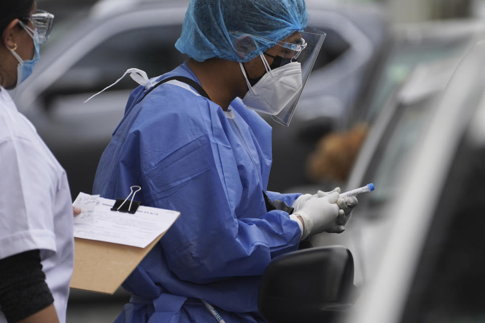 Pharmacy workers gather a sample from a person in a car getting tested for COVID-19 in Mexico City, Monday, Jan. 10, 2022. (AP Photo/Marco Ugarte)