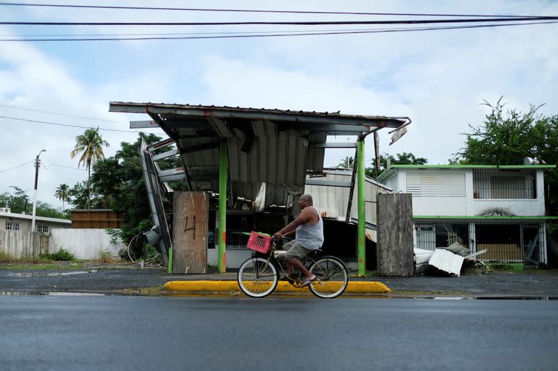 FILE PHOTO: A man rides his bicycle past a gas station that was damaged by Hurricane Maria two years ago, as Tropical Storm Karen approaches in Loiza