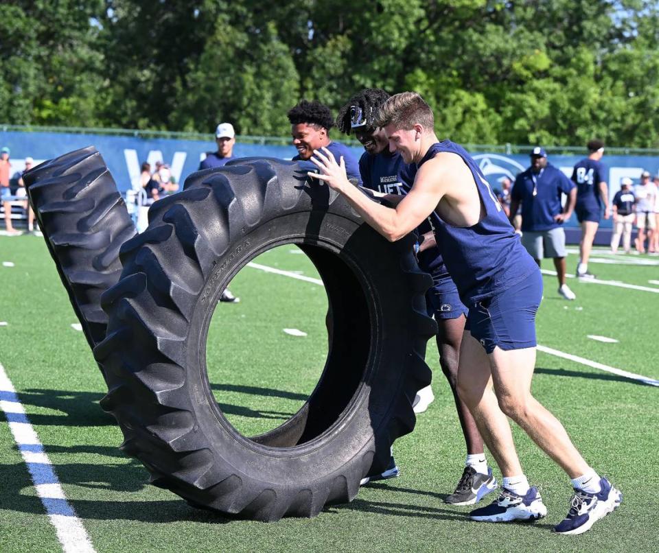 Penn State’s Christian Veilleux, right, and Malick Meiga, center, flip a tire during the Nittany Lions annual Lift For Life event at University Park Thursday, June 30, 2022.