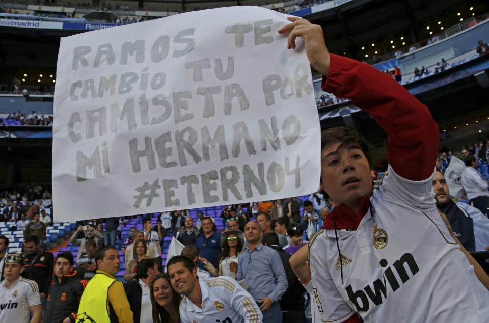 A Real Madrid's fan holds up a poster reading "Ramos, I will exchange my brother for your jersey" as he arrives to attend the Champions League semi-final first leg soccer match against Bayern Munich at Santiago-Bernabeu's stadium in Madrid