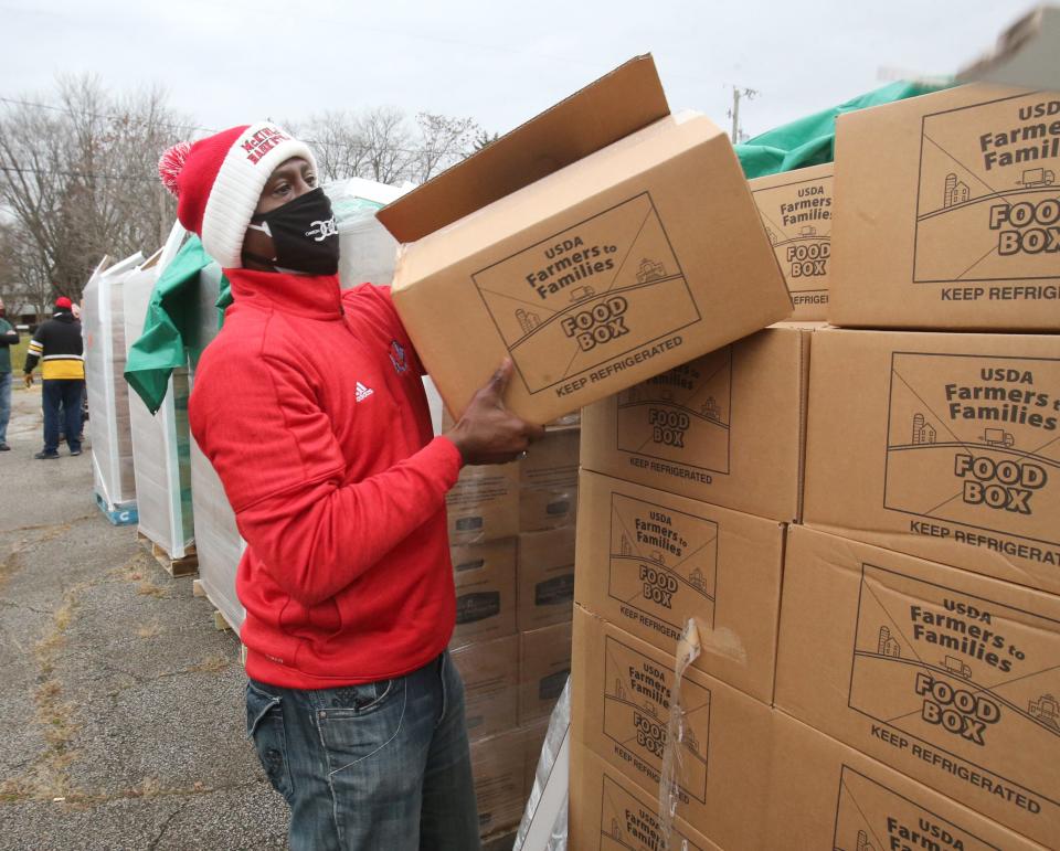 Ronnie Stokes unloads a box as Canton Outside of Canton provided food at St. Paul AME Church in Canton on Saturday, Dec. 12, 2020. A group of former professional athletes who grew up here and moved away provided food that was given away on a first-come, first-served basis. 