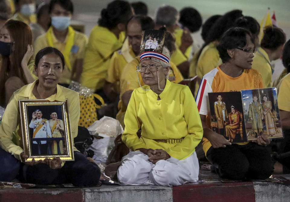 Supporters of the monarchy hold images of Thailand's King Maha Vajiralongkorn and Queen Suthida, as they wait to see their motorcade near Thammasat University in Bangkok, Thailand, Saturday, Oct. 31, 2020. officiating a graduation ceremony at Thammasat University in Bangkok, Thailand, Saturday, Oct. 31, 2020. Thailand’s king has presided over a university graduation ceremony at a stronghold of a protest movement seeking to reduce the monarchy’s powers, after activists issued a call for students to boycott the event. (AP Photo/Sunti Teapia)