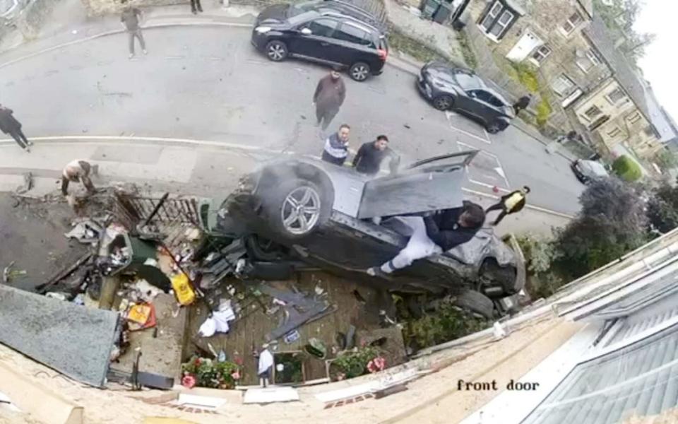 CCTV image of the aftermath of a BMW flipping over and crashing into a front garden