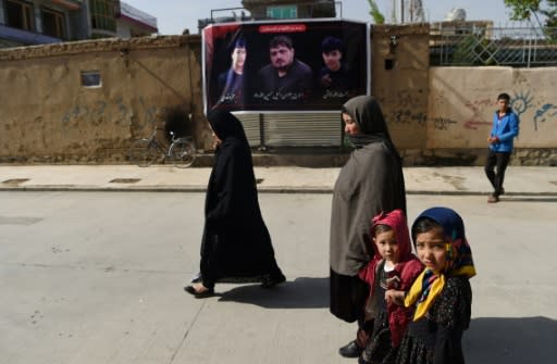 People walk past a banner bearing the image of Wakil Hussain Allahdad, 32, one of the 57 victims of a suicide blast on a voter registration centre in Kabul, in the city on April 23, 2018