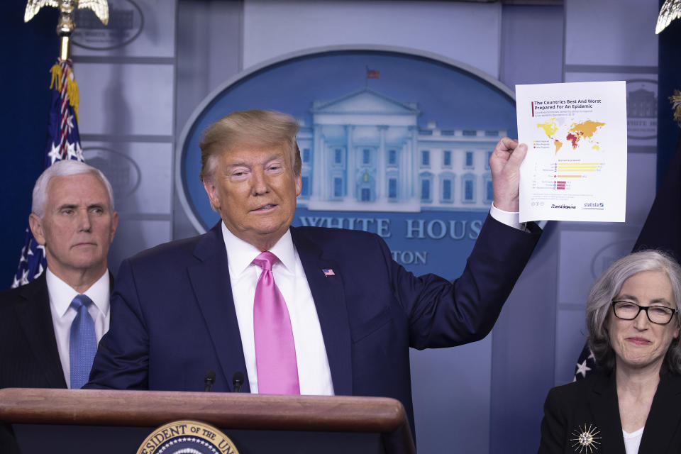 President Donald Trump, wearing a wry smile and with Vice President Mike Pence at his side, holds up a stack of papers.