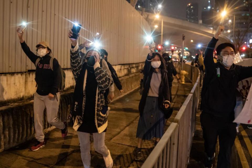 Supporters wave cellphone lights as they see a Correctional Services Department (CSD) vehicle following the forth day of a bail hearing for 47 opposition activists