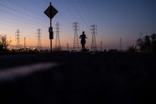 PHOTO: A woman jogs by power lines as a wave of extreme heat settled over much of California, in Mountain View, Calif., Aug. 17, 2022.  (Carlos Barria/Reuters, FILE)