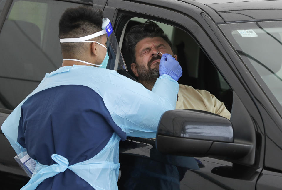 A man receives a COVID-19 test at a drive through testing station at a beach in Sydney, Australia, Saturday, Dec. 19, 2020. Sydney's northern beaches will enter a lockdown similar to the one imposed during the start of the COVID-19 pandemic in March as a cluster of cases in the area increased to more than 40. (AP Photo/Mark Baker)
