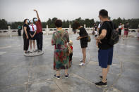 People wearing face masks to protect against the coronavirus pose for a selfie at the Temple of Heaven in Beijing, Saturday, July 18, 2020. Authorities in a city in far western China have reduced subways, buses and taxis and closed off some residential communities amid a new coronavirus outbreak, according to Chinese media reports. They also placed restrictions on people leaving the city, including a suspension of subway service to the airport. (AP Photo/Mark Schiefelbein)