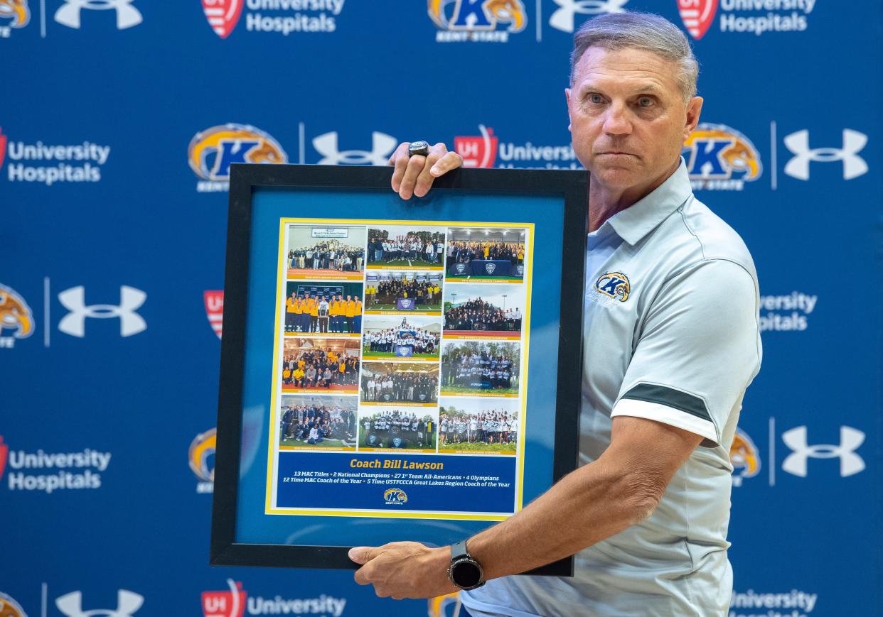 Kent State Director of Track and Field/Cross Country Bill Lawson displays a plaque he received commemorating his 13 MAC championship teams during a press conference at the M.A.C. Center on Monday, when Lawson announced his retirement from coaching.