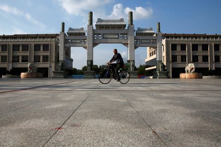 A man cycles through the largely empty Commercial Street in the New Zone urban development in Dandong, Liaoning province, China September 11, 2016. REUTERS/Thomas Peter