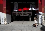 Passersby holding sunshades walk past decorations celebrating the upcoming Tokyo 2020 Olympic and Paralympic Games at Nihonbashi district in Tokyo