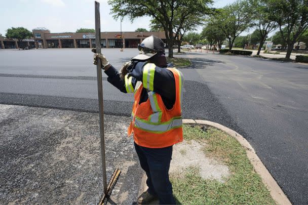 PHOTO: Miguel takes a break from shoveling asphalt during a parking lot resurfacing job in Richardson, Texas, June 20, 2023. (Lm Otero/AP)