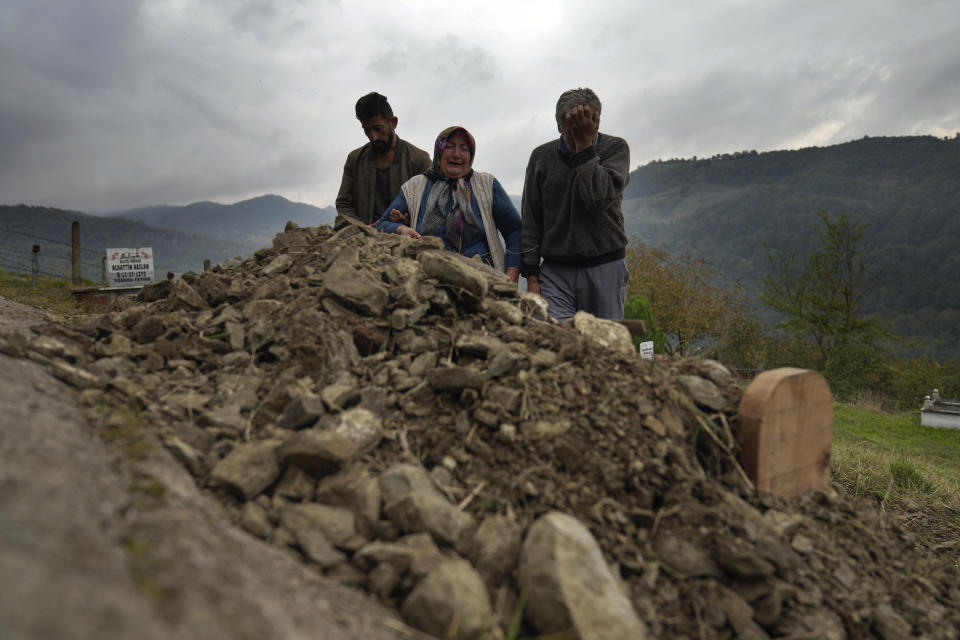 Habibe Ayvaz, 63, and Recep Ayvaz, 62, parents of the miner killed in a coal mine explosion, Selcuk Ayvaz, 33, weep over his grave in Amasra, in the Black Sea coastal province of Bartin, Turkey, Sunday, Oct. 16, 2022. (AP Photo/Khalil Hamra)