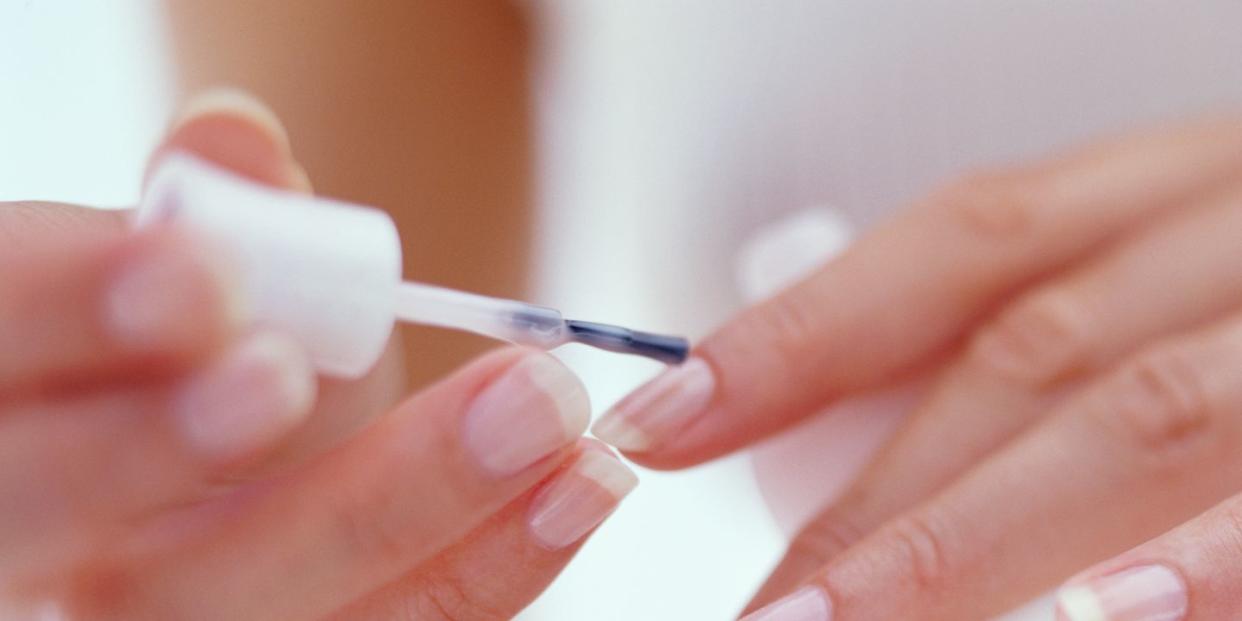 young woman painting fingernails close up