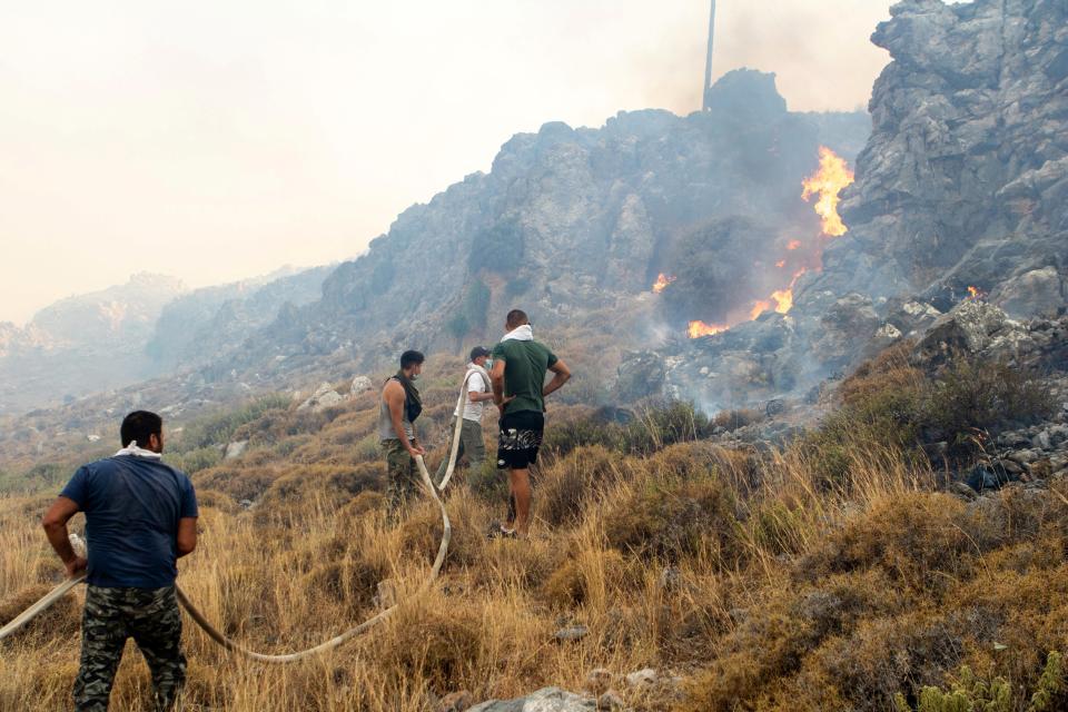 People try to extinguish a wildfire burning near Lindos (REUTERS)