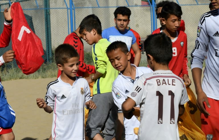 At a makeshift beach in landlocked Afghanistan, children as young as eight, wearing baggy Real Madrid and Barcelona shirts with "Ronaldo" and "Bale" printed on the back, joyfully kick and chase the ball