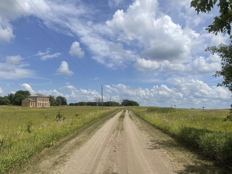A gravel road runs through prairie land, and a brick building at the site of a former employee duplex, in the Upper Sioux Agency State Park near Granite Falls, Minn., on July 28, 2023. Minnesota is taking the rare step of transferring the state park with a fraught history back to a Dakota tribe, trying to make amends for events that led to a war and the largest mass hanging in U.S. history. (AP Photo/Trisha Ahmed)