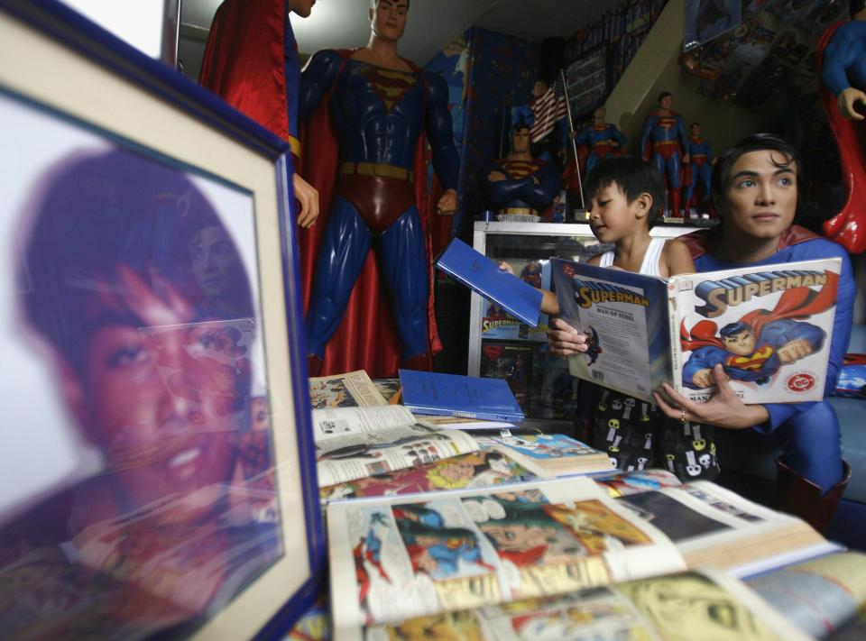 Herbert Chavez holds a Superman book as he shows his collection to a boy inside his house in Calamba Laguna, south of Manila